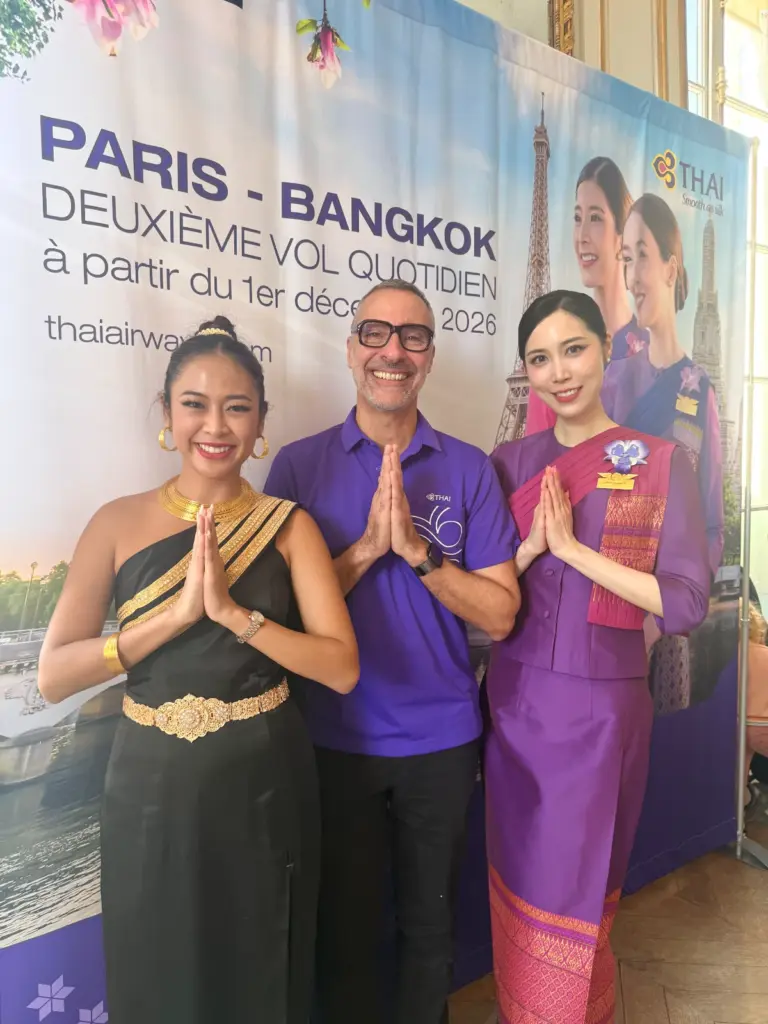 Jenny et deux représentants de Thai Airways posent devant un panneau promotionnel de la compagnie aérienne.