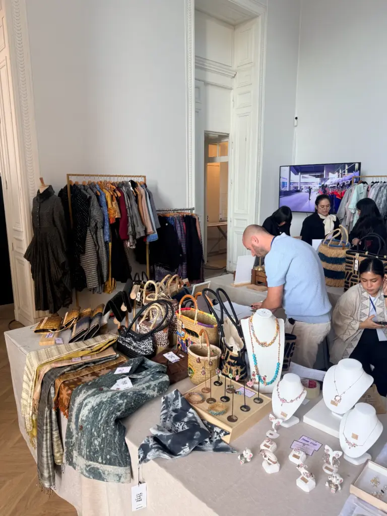 Stand proposant des vêtements, bijoux et accessoires exposés sur des portants et des tables.