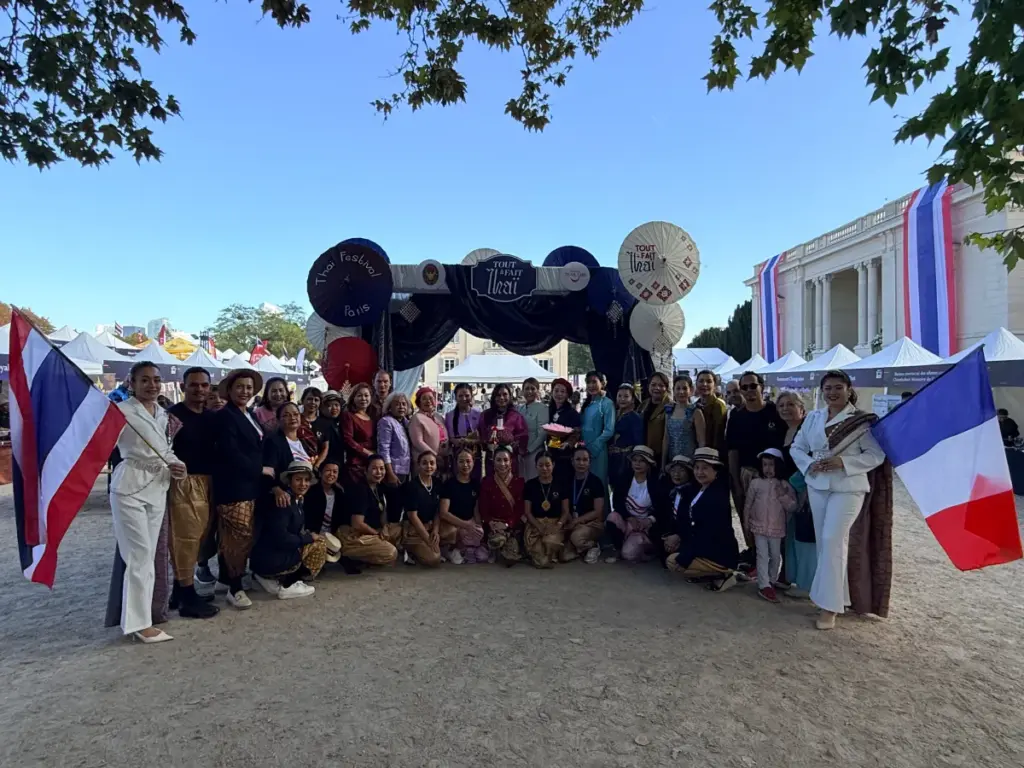 Photo de groupe réunissant de nombreux participants sous l'arche décorative du festival Tout à fait Thaï au Parc de Bagatelle.