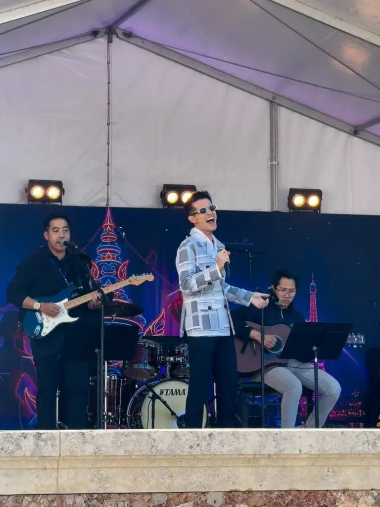 Deux artistes masculins chantent sur la scène du festival sous une tente blanche.