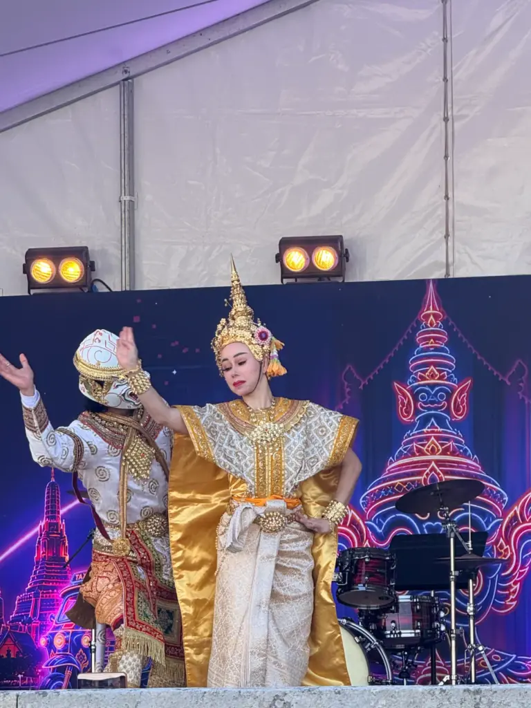 Danseuse vêtue d'un costume traditionnel rouge exécutant un mouvement des bras sur la scène du festival.