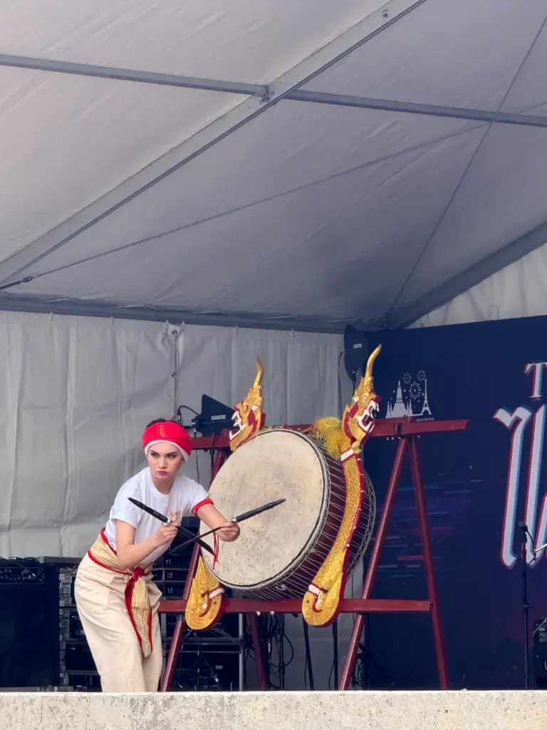 Artistes en costumes traditionnels thaïlandais réalisant une performance chorégraphiée sur scène.