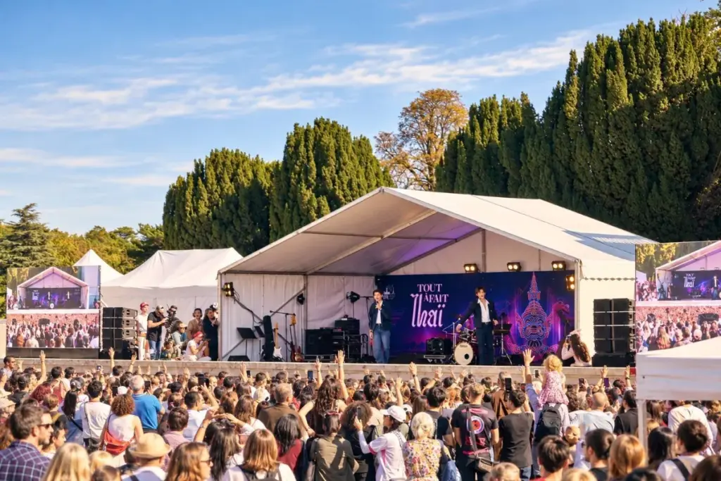 Vue générale d'une scène du festival Tout à fait Thaï avec deux artistes et une foule nombreuse devant le podium.